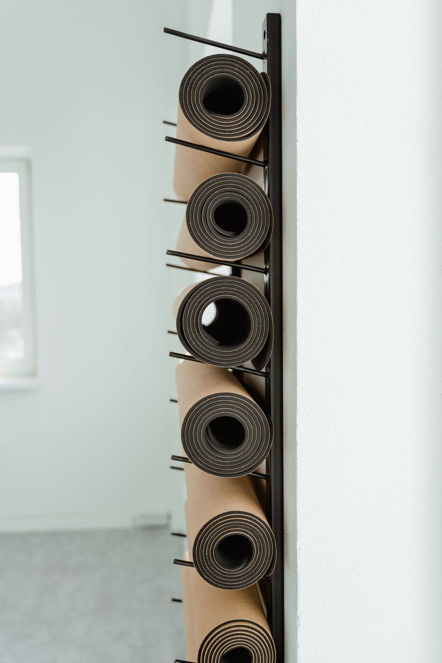 Yoga mats rolled on a wall rack in a bright studio